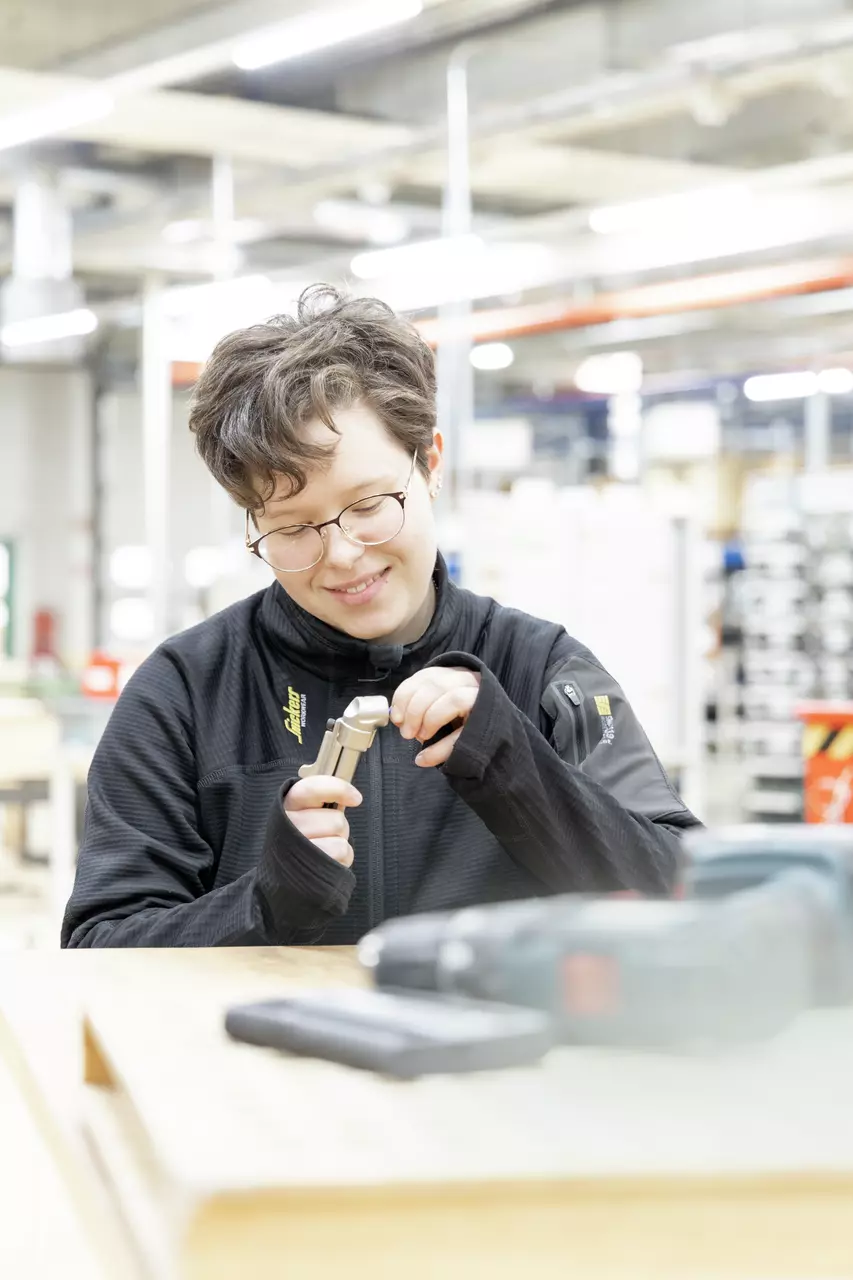 Person in workshop holding and examining a tool