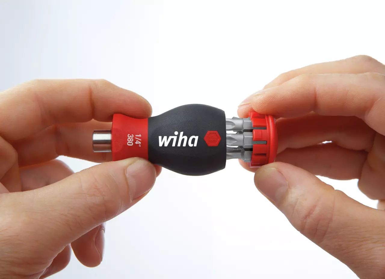 Hands holding a black and red bit holder with multiple bits