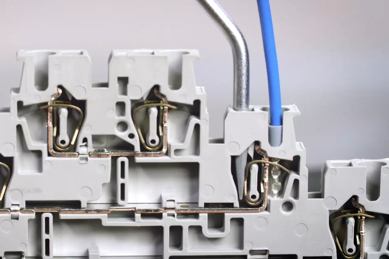 Grey terminal block with metal components and blue wire inserted.