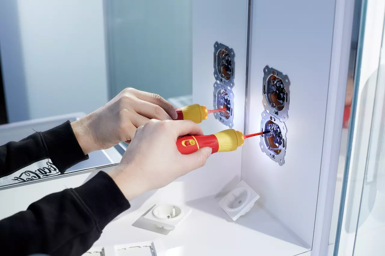 Hands using electric screwdriver on wall sockets