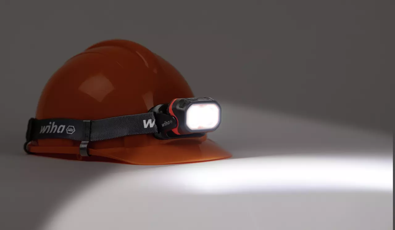 Orange hard hat with headlamp emitting bright light.