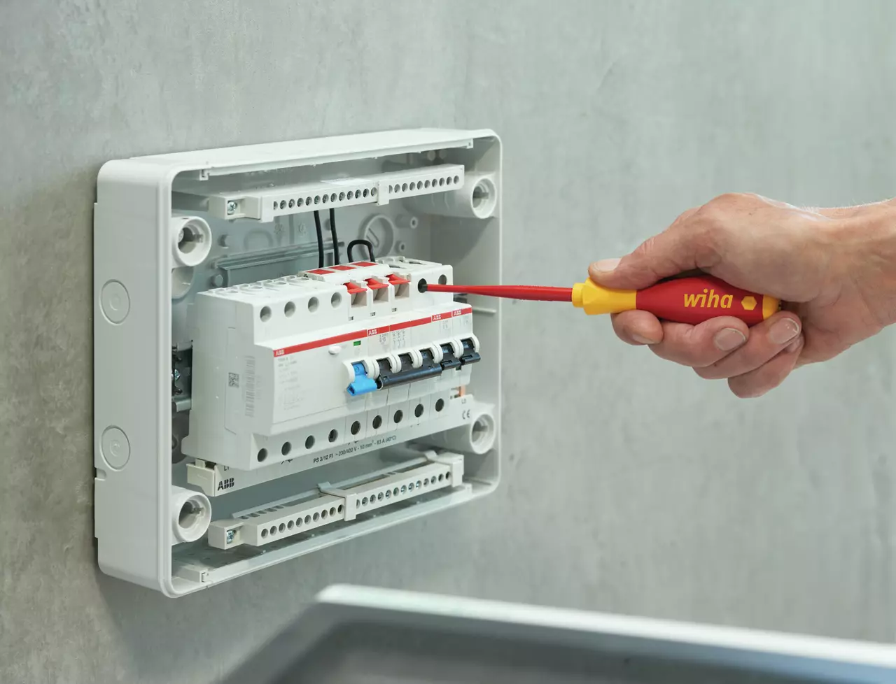 A person uses an insulated screwdriver on an electrical panel
