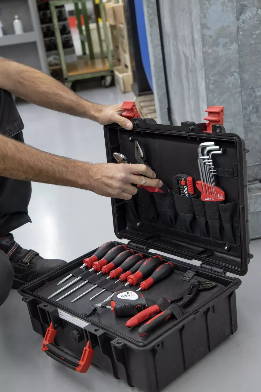 A person opening a tool case with various hand tools and screwdrivers inside.
