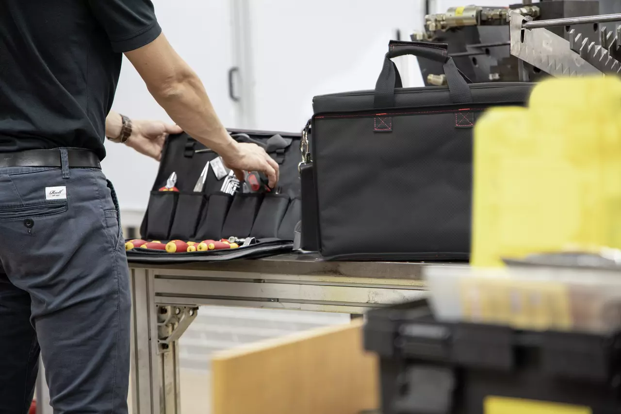Technician organizing tools in a black case on a workbench.