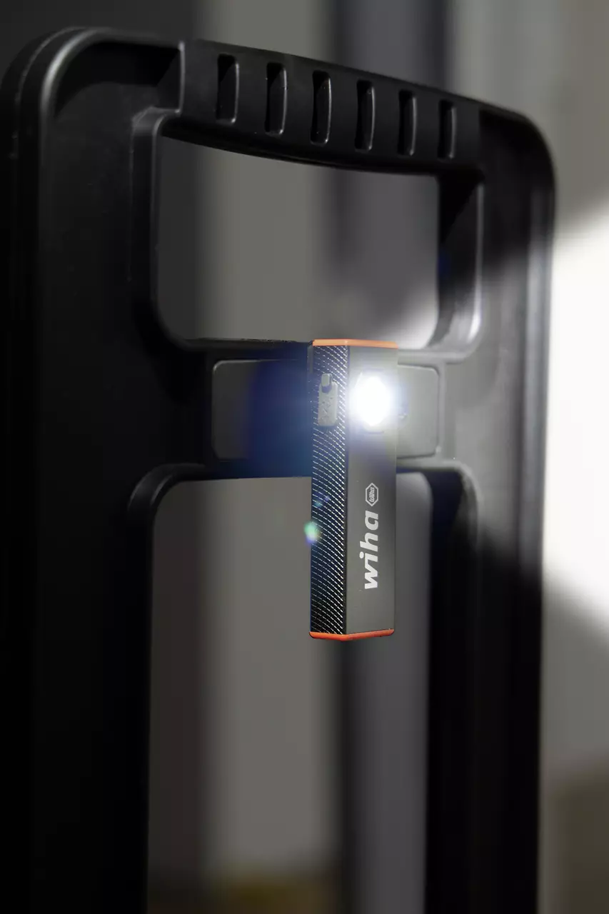 Black magnetic hand light attached to a black handle, emitting bright white light