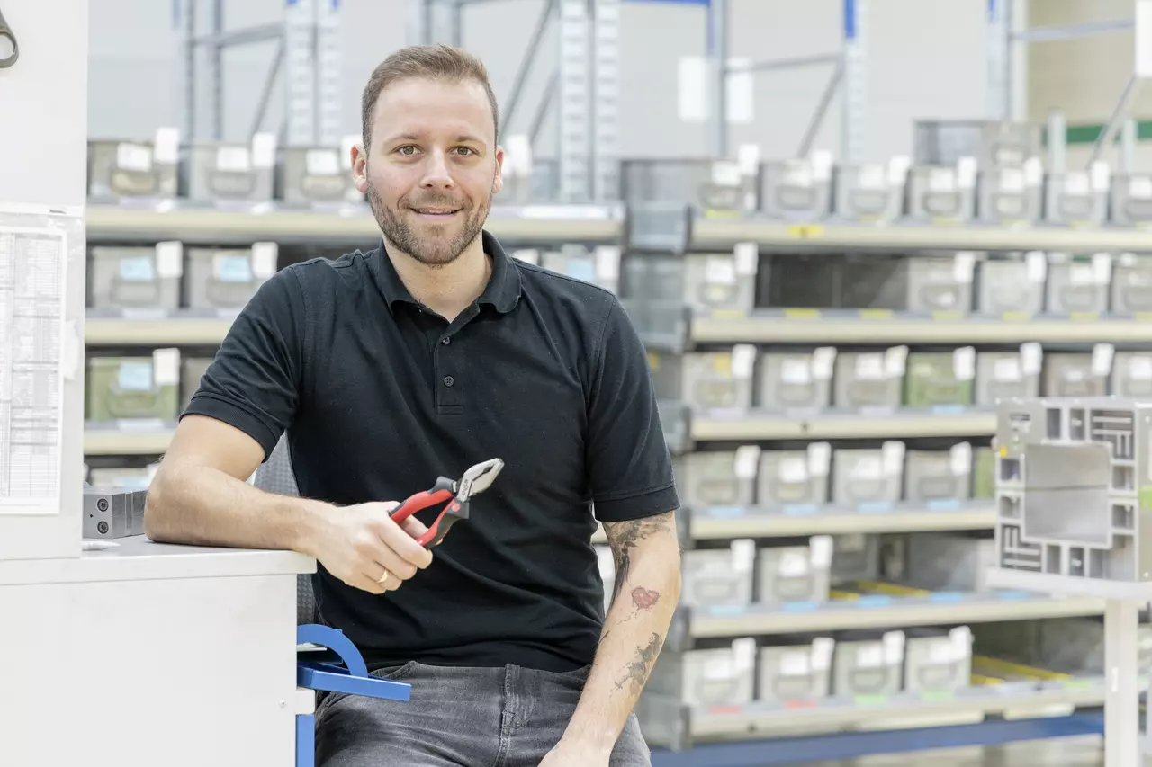 Person holding combination pliers in a warehouse