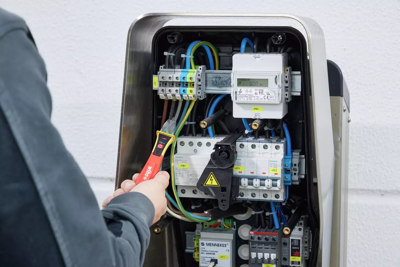 Person using non-contact voltage detector on electrical panel