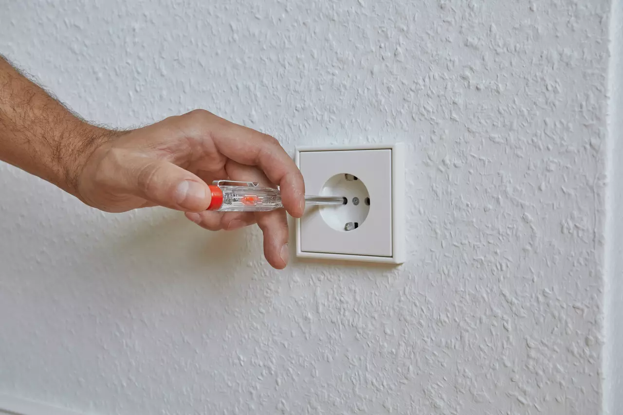 Ruka používá zkoušečku napětí na zásuvce