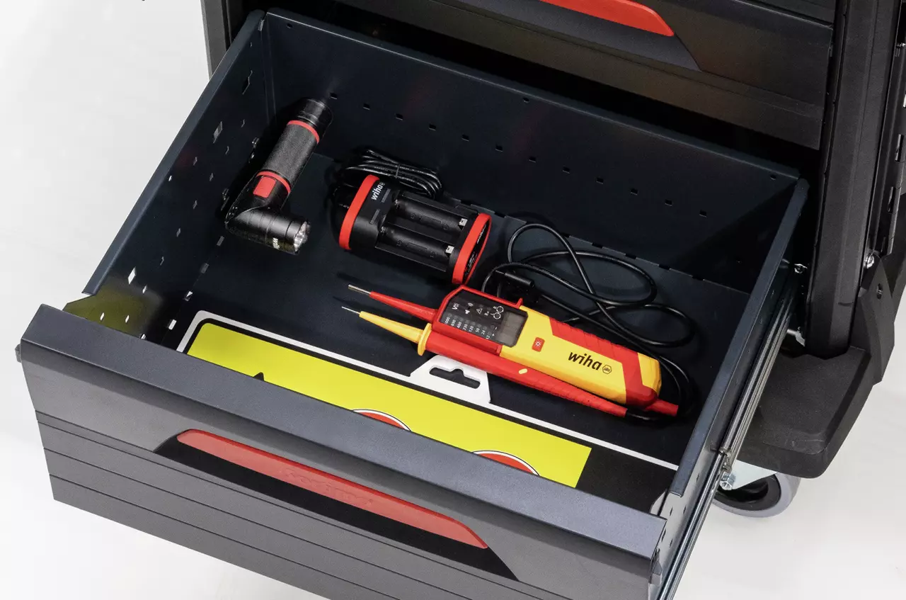 Open drawer with tools including a flashlight, battery charger, and voltage tester