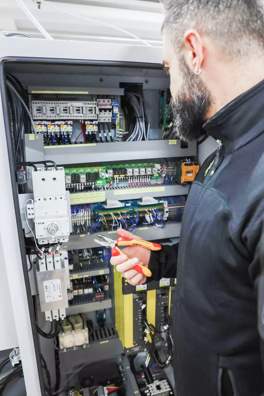 Person using pliers to work on an electrical panel