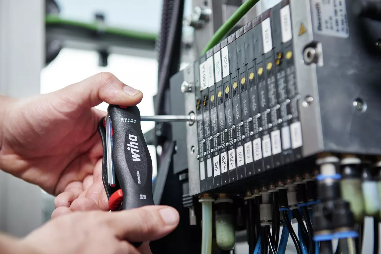 Person using a folding hex key tool on an electrical panel.