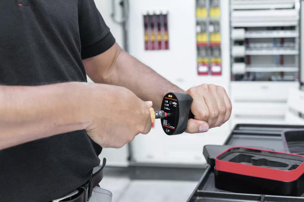 A person using a torque quick check tool with a screwdriver in a technical setting.