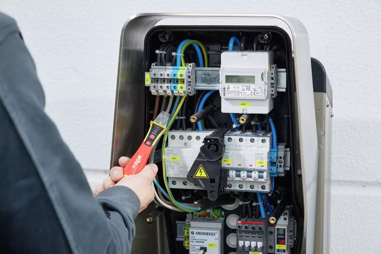 Person using a non-contact voltage detector on electrical panel