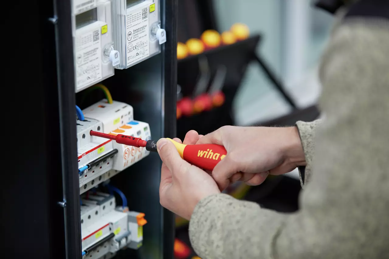 Person using an electric screwdriver on an electrical panel