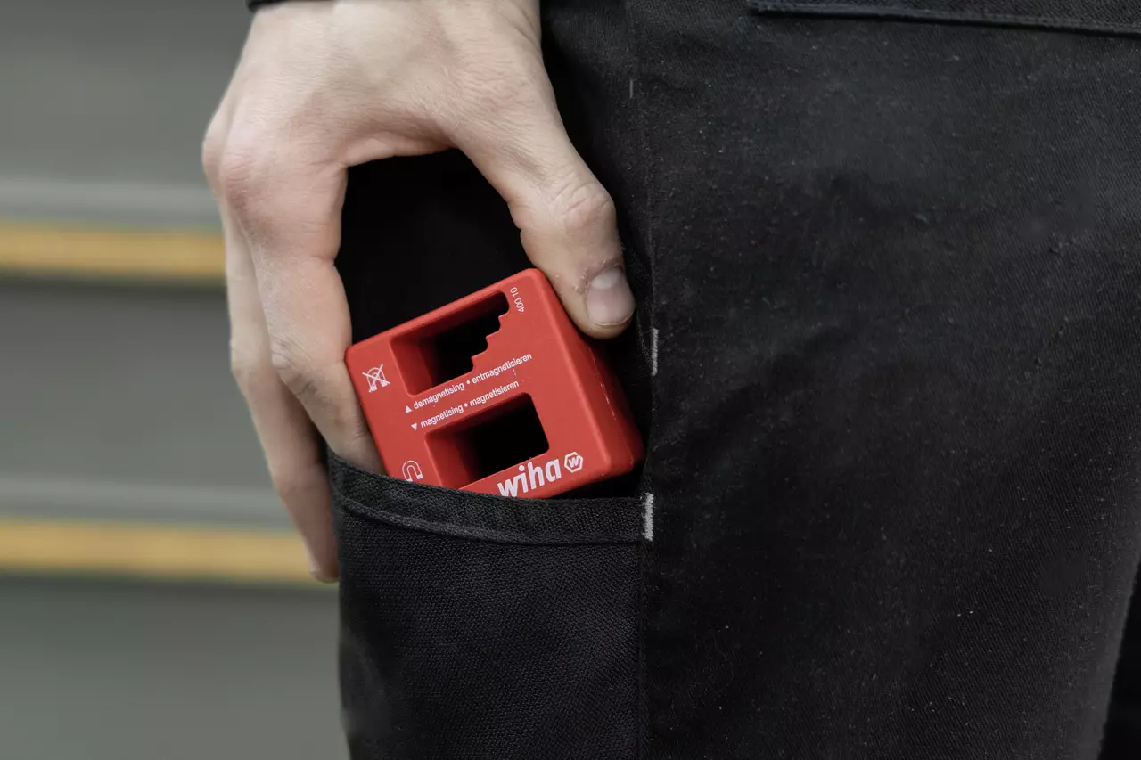 A person placing a red magnetizer tool into a pocket.