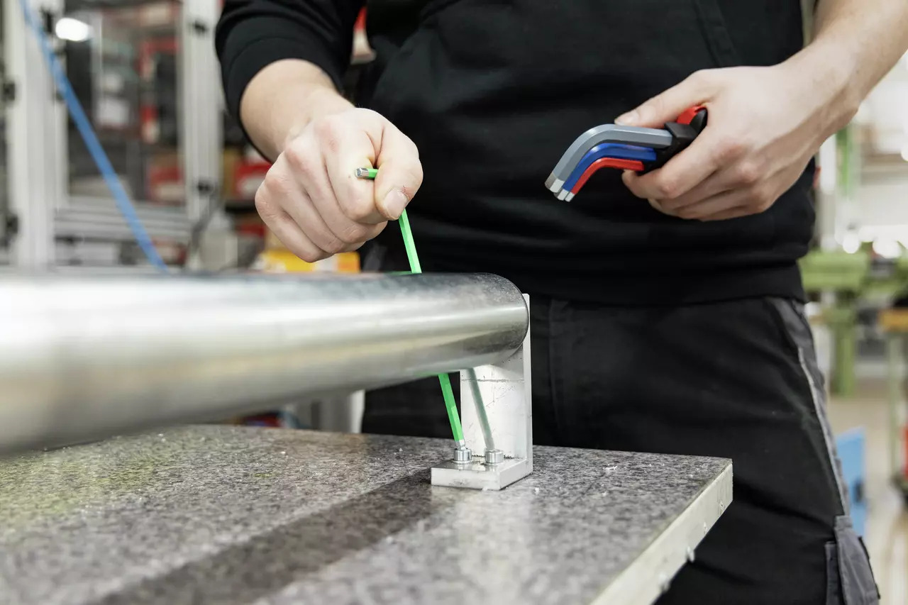 Person using a green L-key on a metal fixture, holding more colored L-keys.
