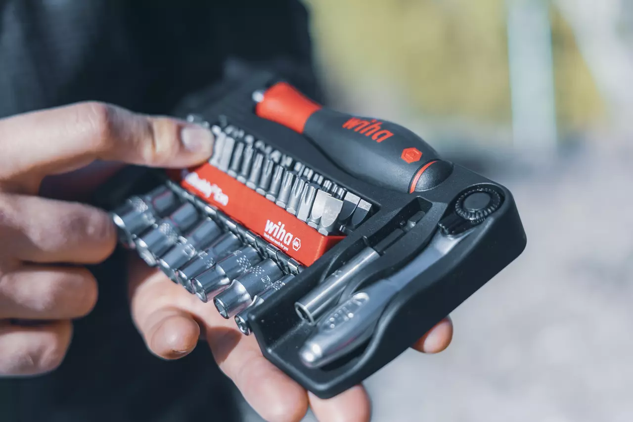 Person holding a tool kit with various screwdriver bits and sockets.