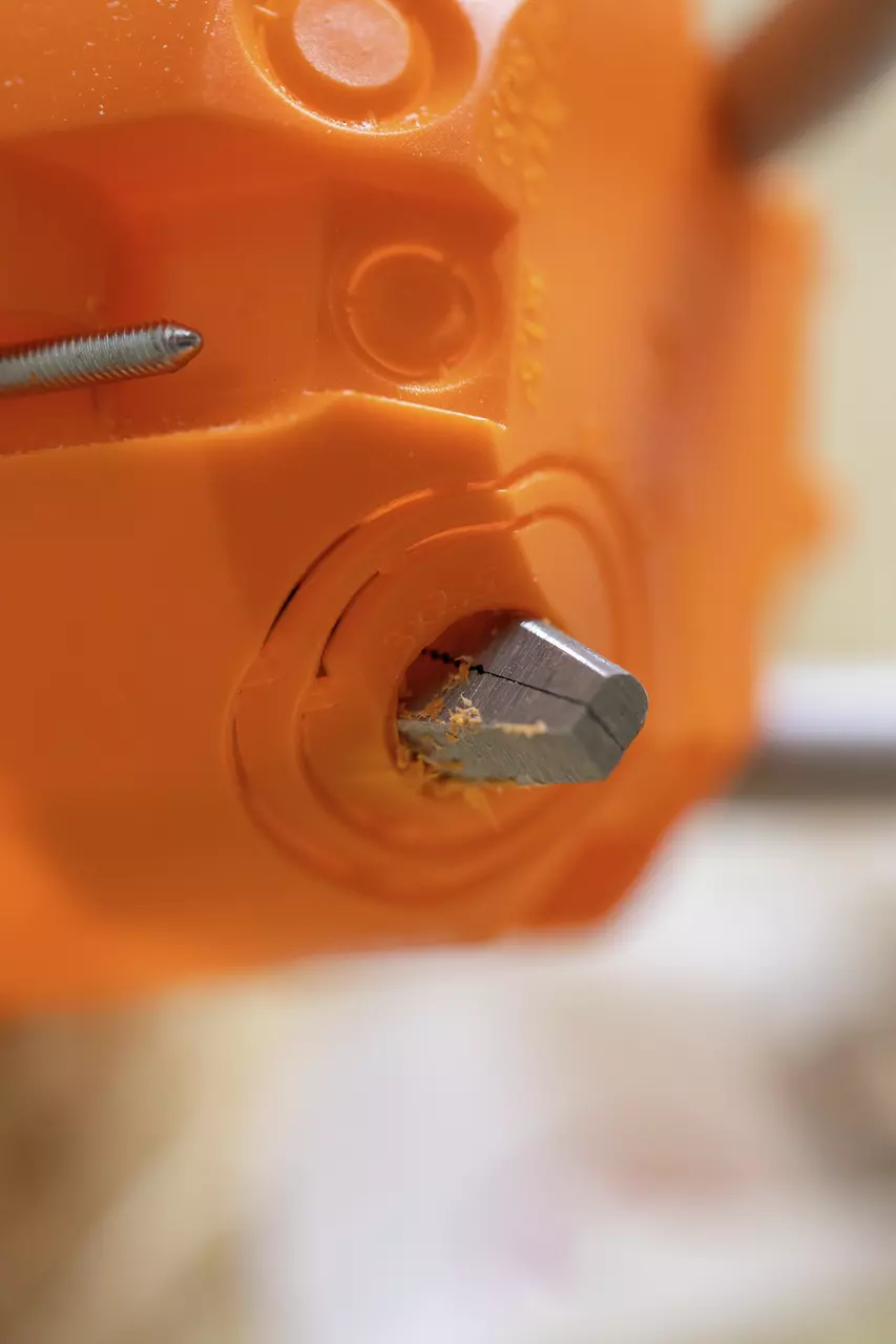 Close-up van een oranje plastic gereedschap met een ingevoegde metalen schroef.