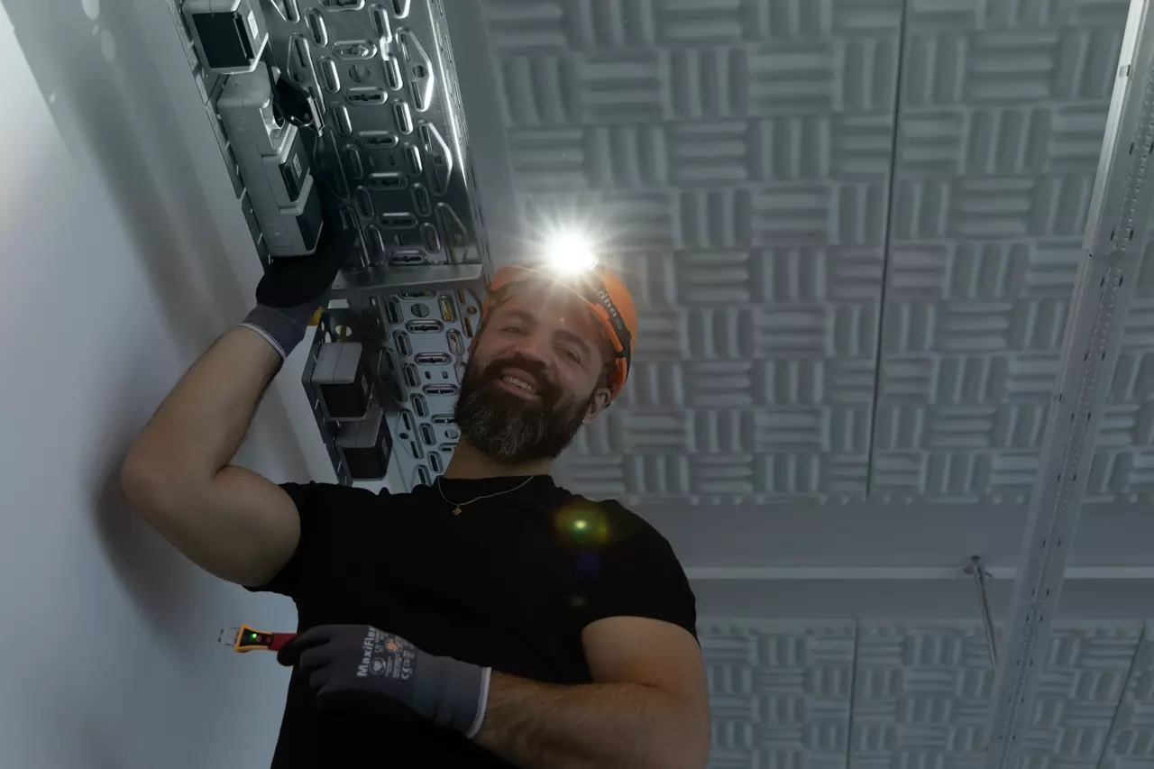 A person wearing a headlamp and helmet works on a ceiling installation