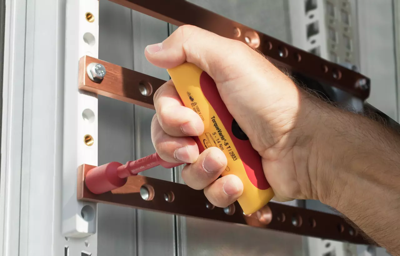 Hand using an electric screwdriver on metal components.