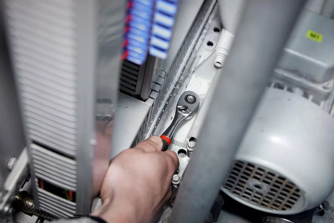 A person uses a ratchet wrench in a mechanical setting.