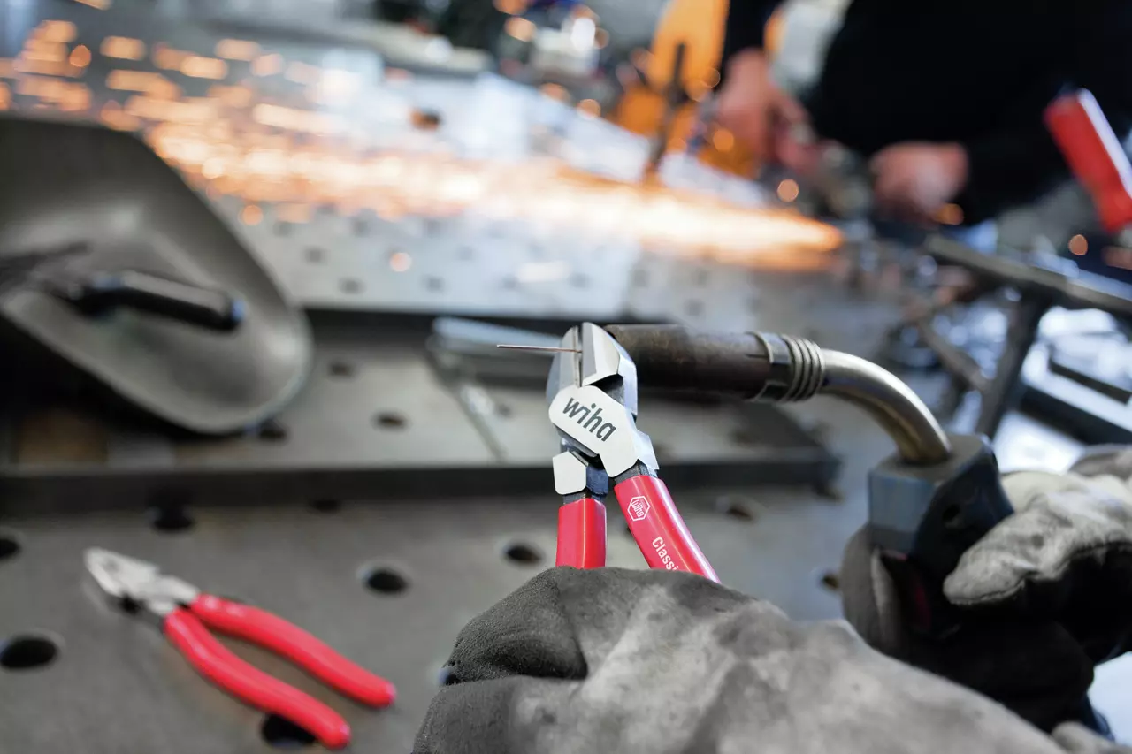 Person using diagonal cutters with red handles on a workbench