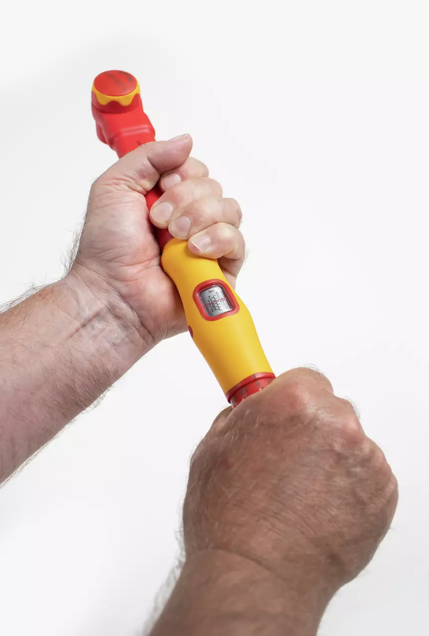 A person holding a yellow and red torque wrench, adjusting it with both hands.