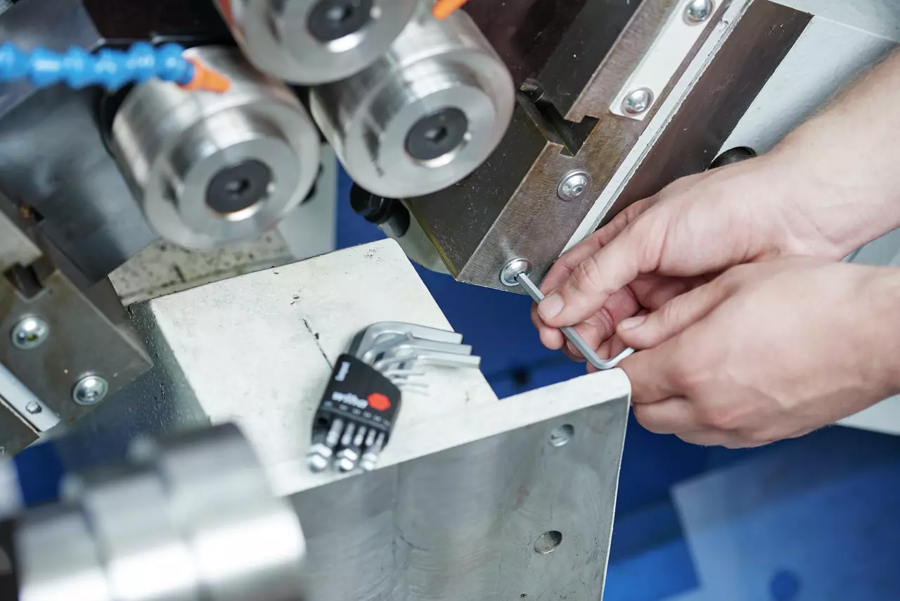 Person using hex key to adjust machine