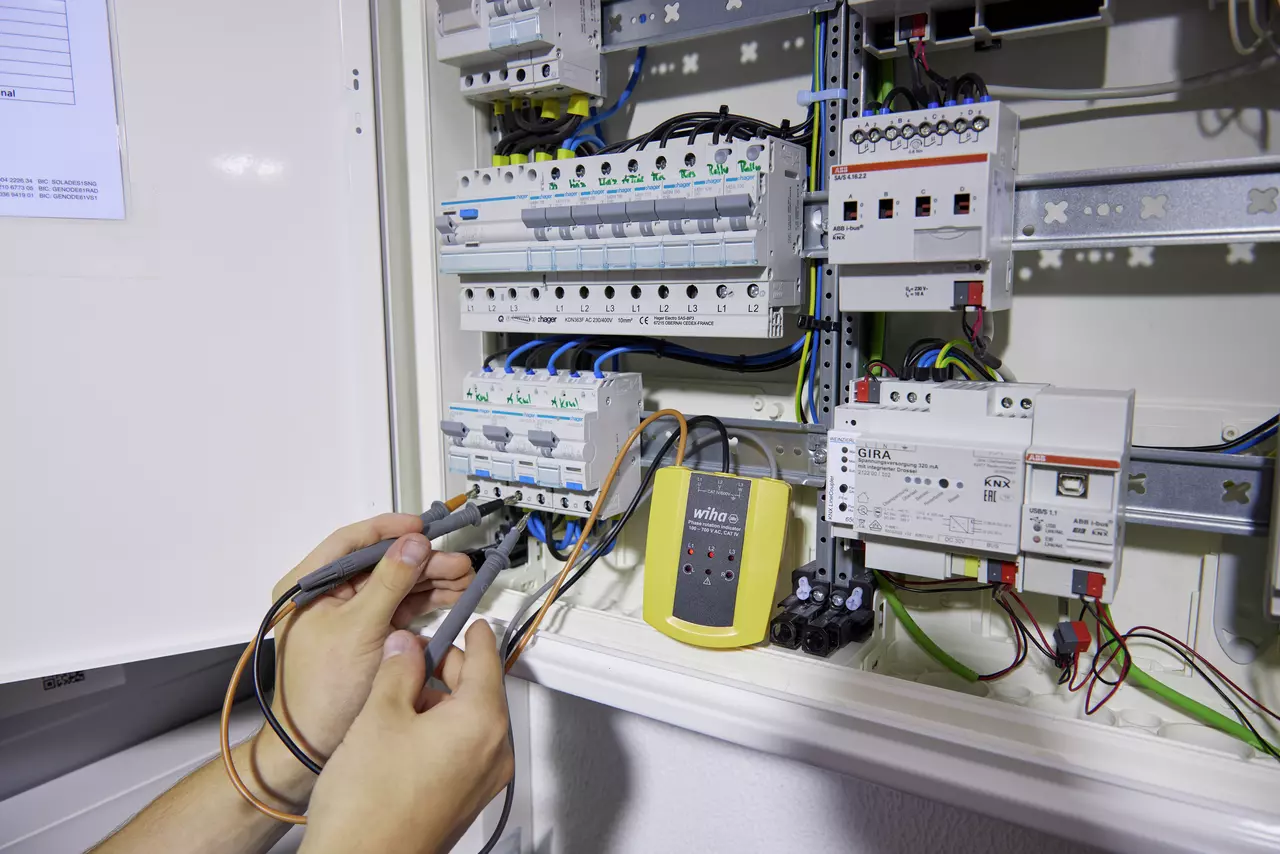 A person using a rotational field indicator in an electrical control cabinet.