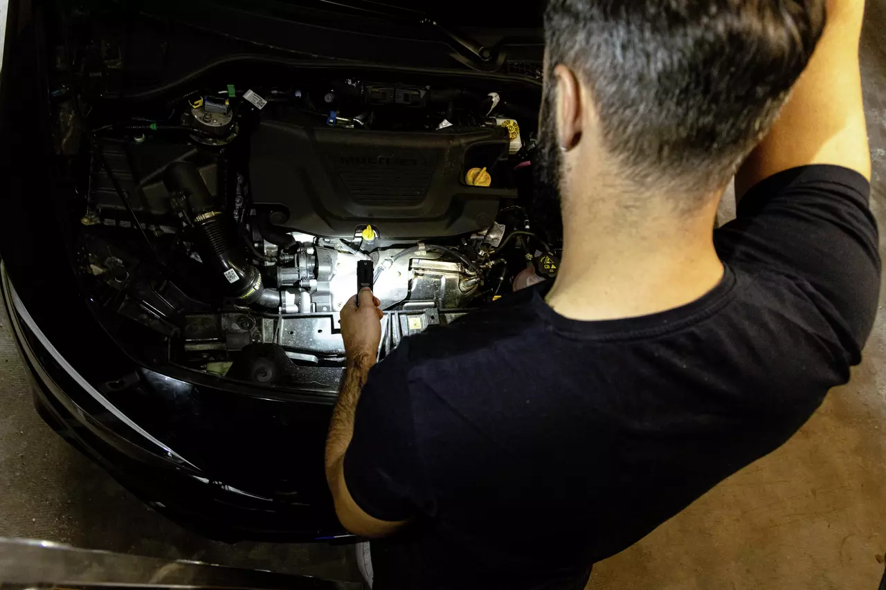 Person using flashlight to inspect car engine