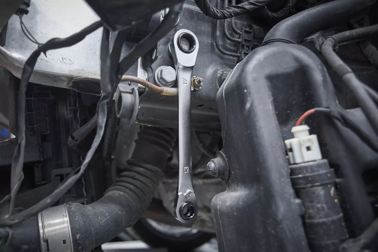 Une clé à cliquet est utilisée sur un boulon dans le compartiment moteur d'une voiture.