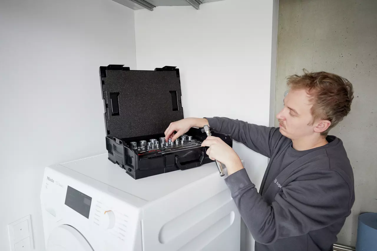 Man using socket wrench set on washing machine