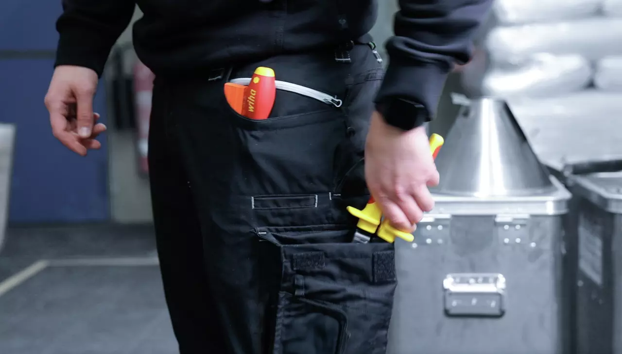 Person holding tools in black work pants pocket