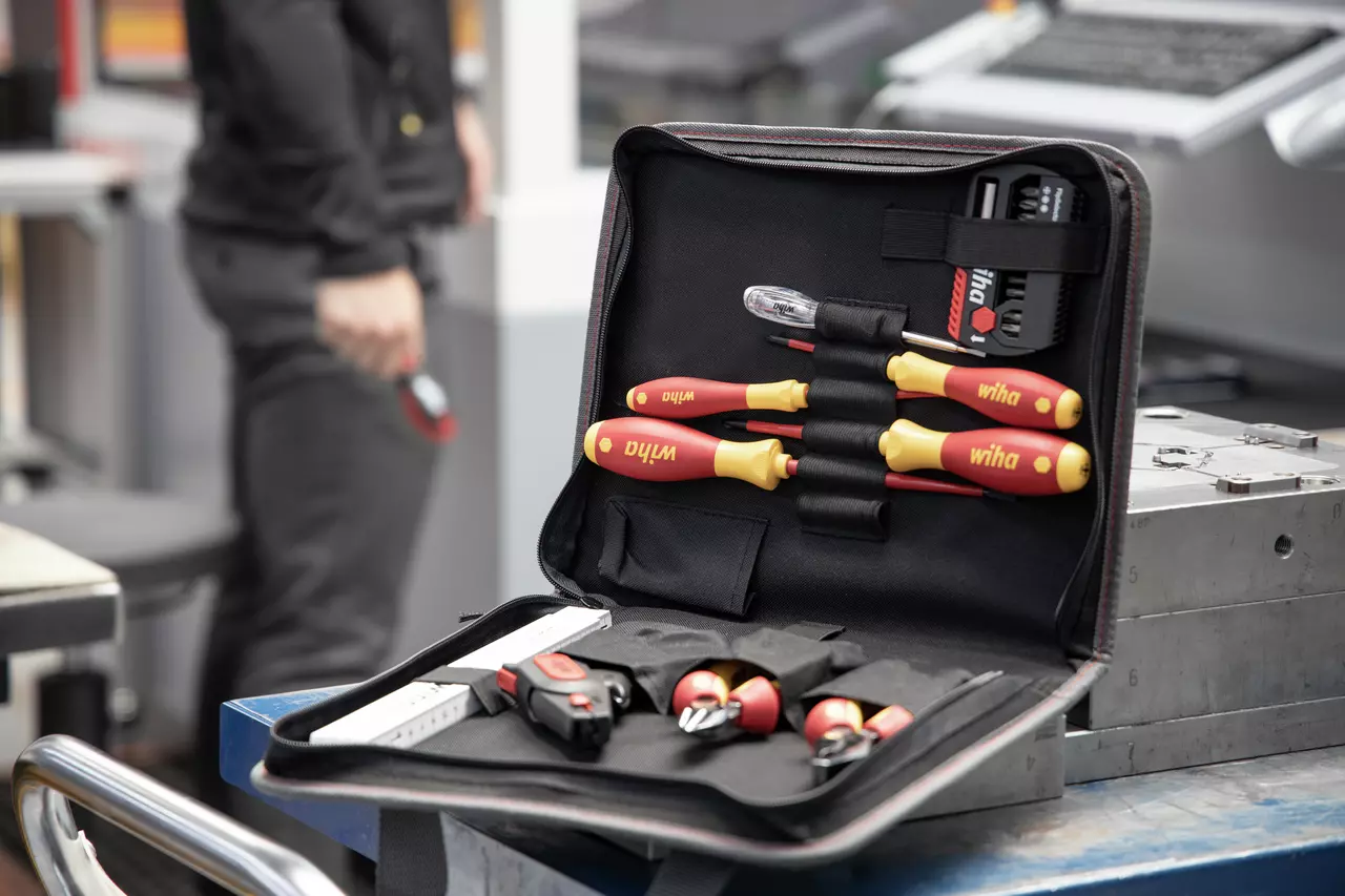 Tool set in open case with screwdrivers on table, person in background.