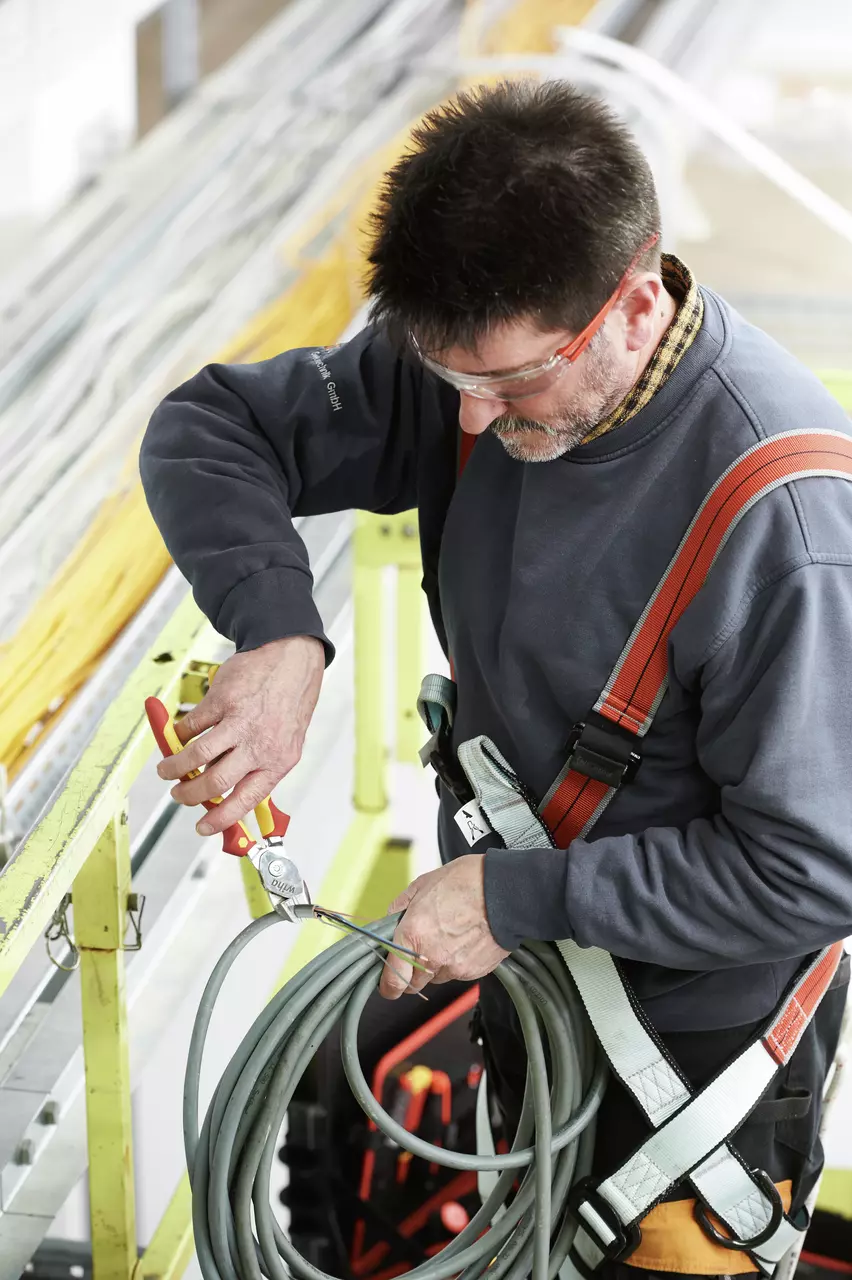 Person using pliers to cut a cable while wearing safety gear