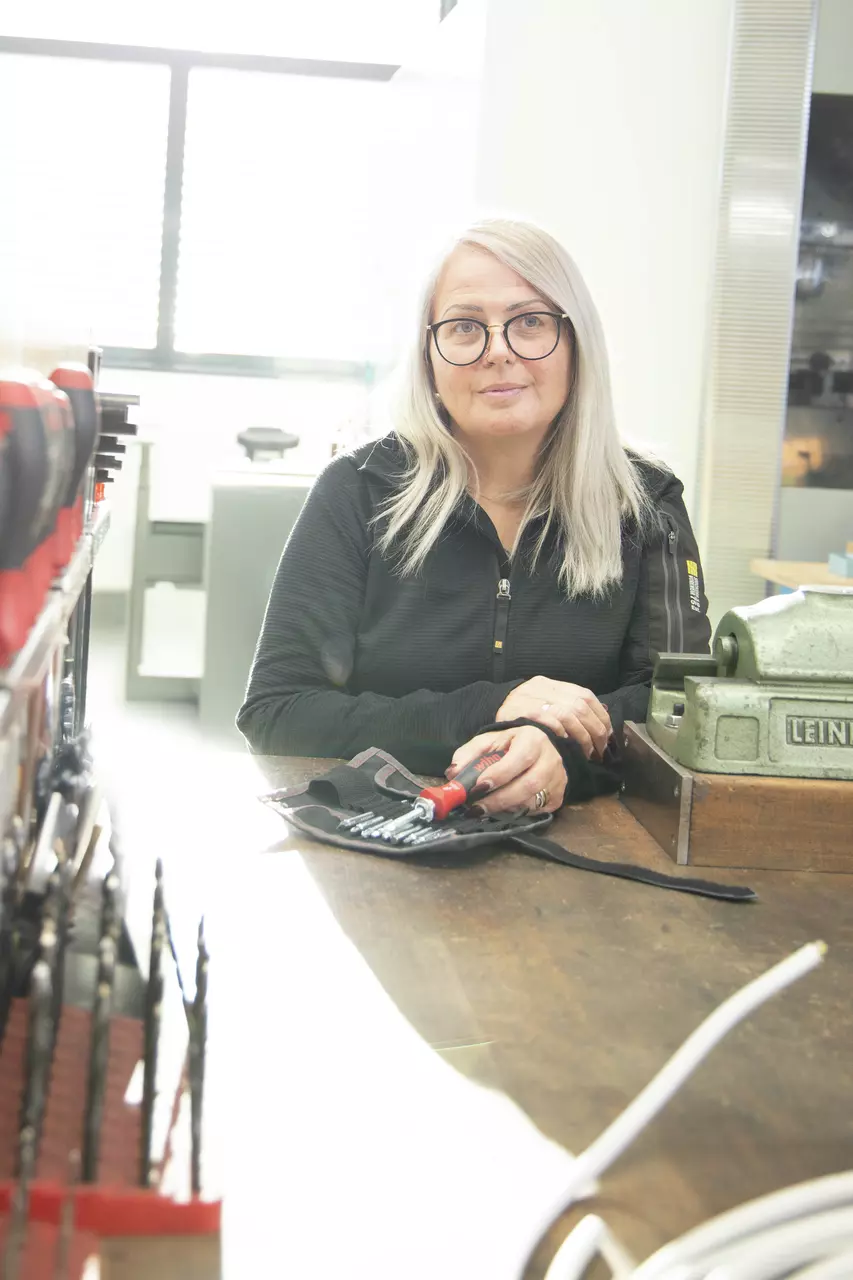 A person sitting at a table holding a screwdriver set.