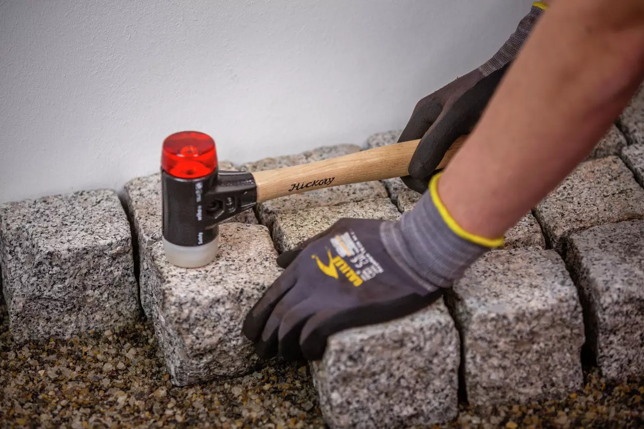 Person using mallet on paving stones