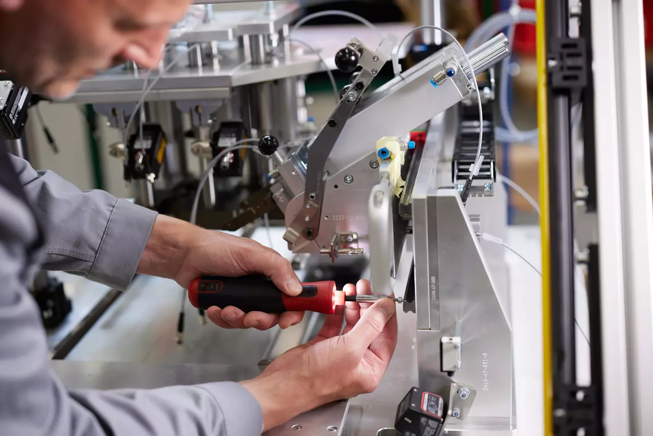Person using an electric screwdriver on a machine