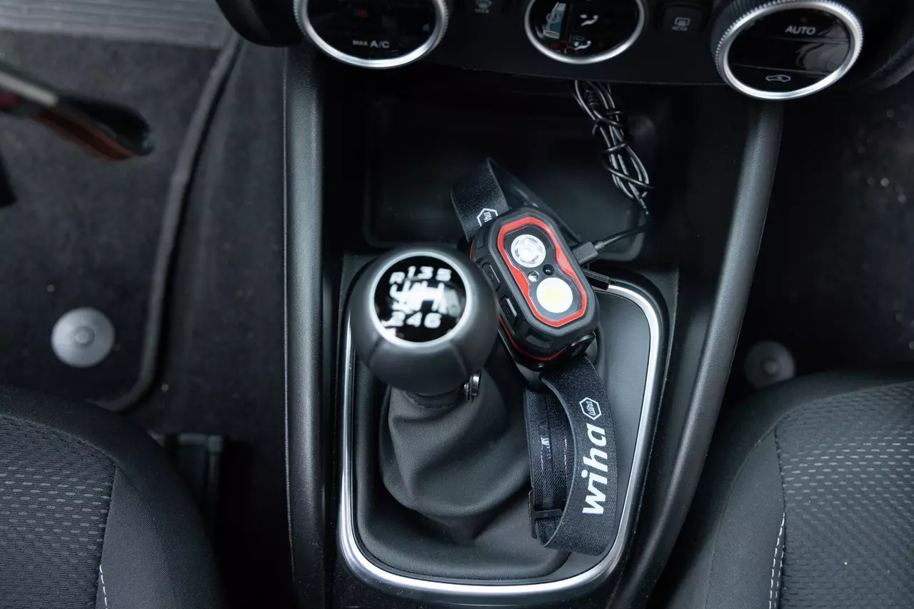 A headlamp with a charging cable placed on a car gear shift area.