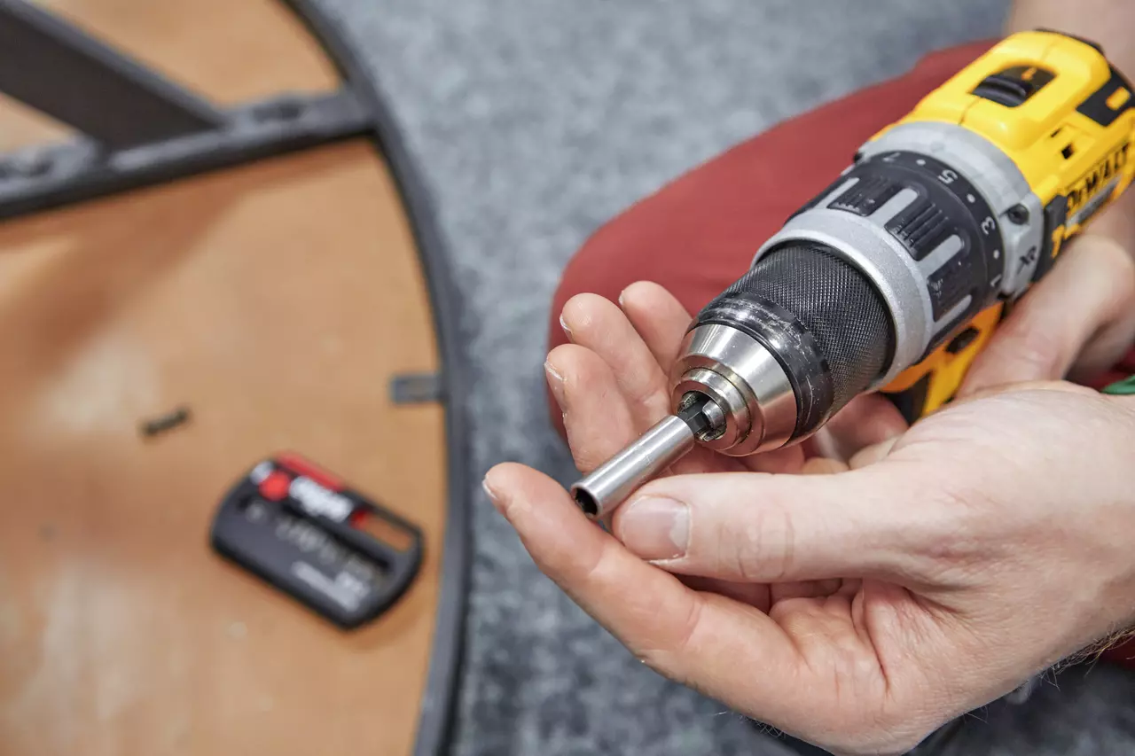 A person holding a yellow cordless drill with a socket attachment.