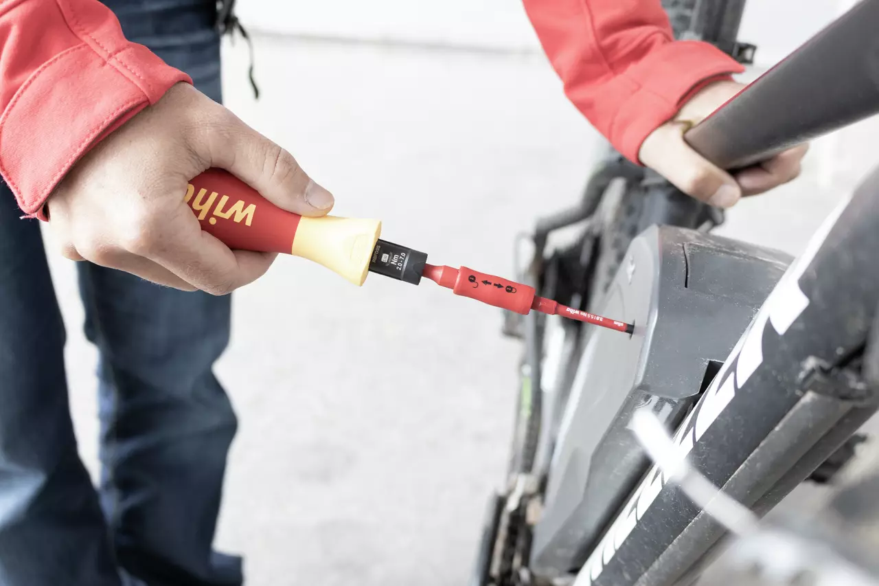 Person using insulated screwdriver on bicycle component