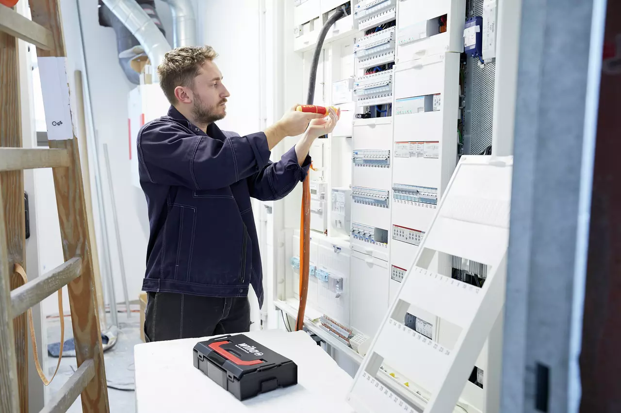 Man working with electric screwdriver on a control cabinet