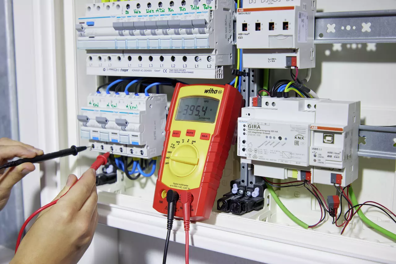 Digital multimeter measuring voltage in an electrical cabinet