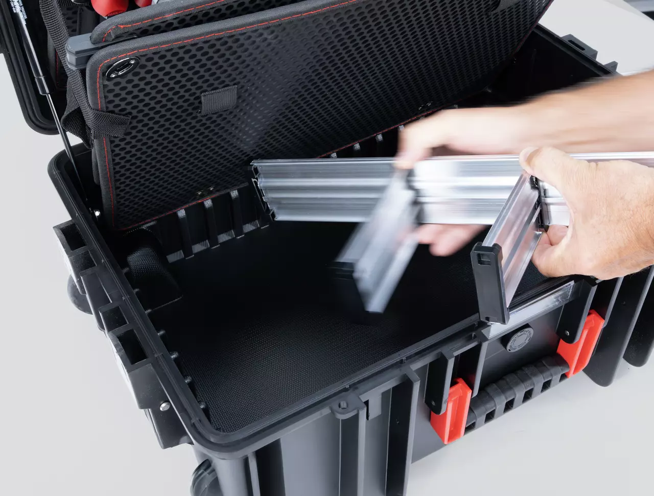 Open tool case with black interior, into which metal profiles are being placed.