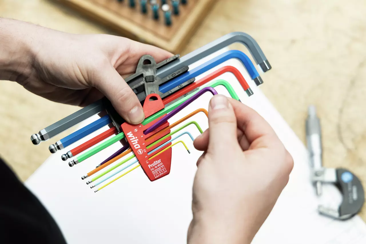 Person holding a set of colorful L-keys in a red holder, adjusting one key.