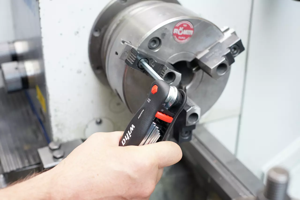 A person using a folding hex key tool on a metal machine part.