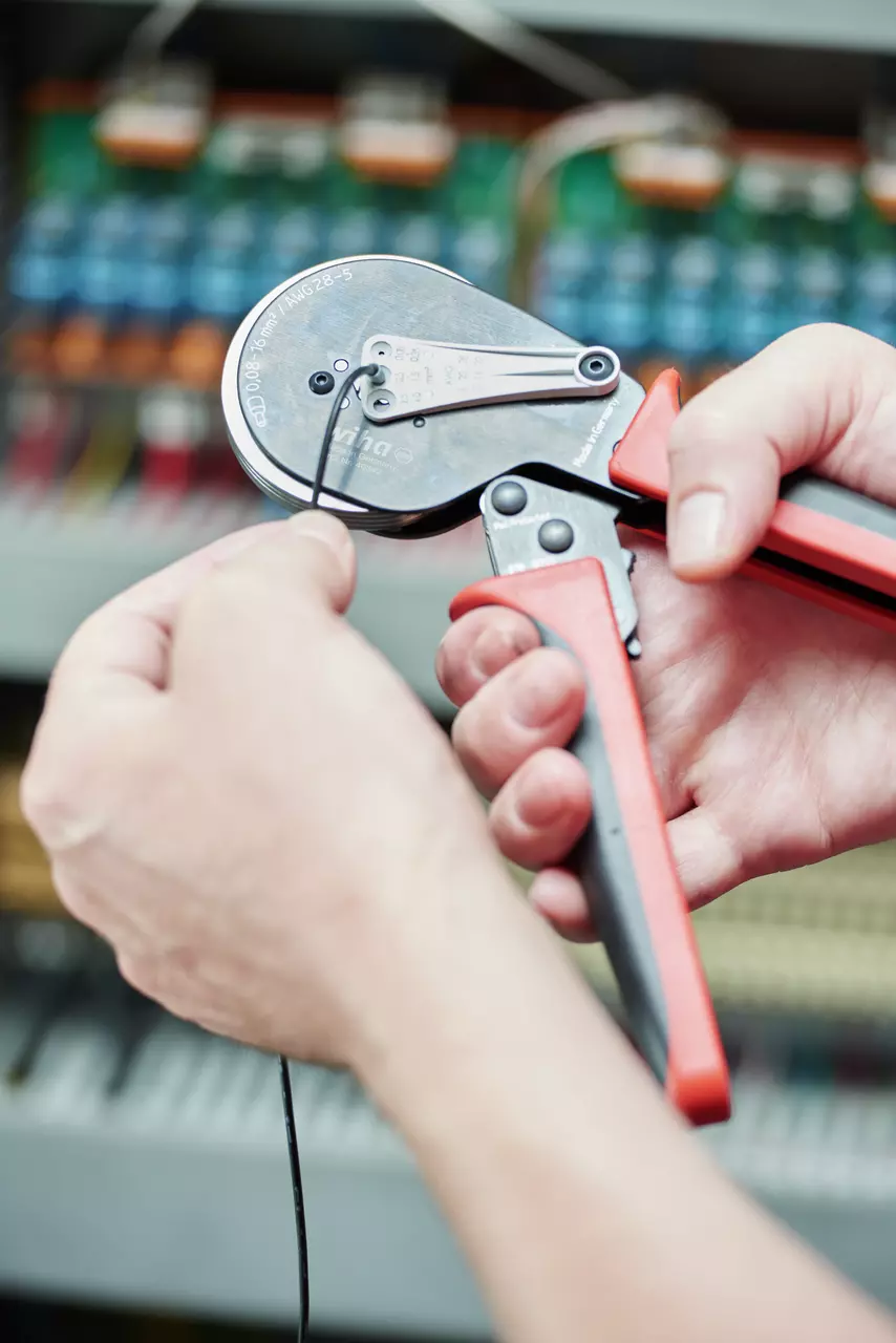 Hands using automatic crimping pliers on a wire