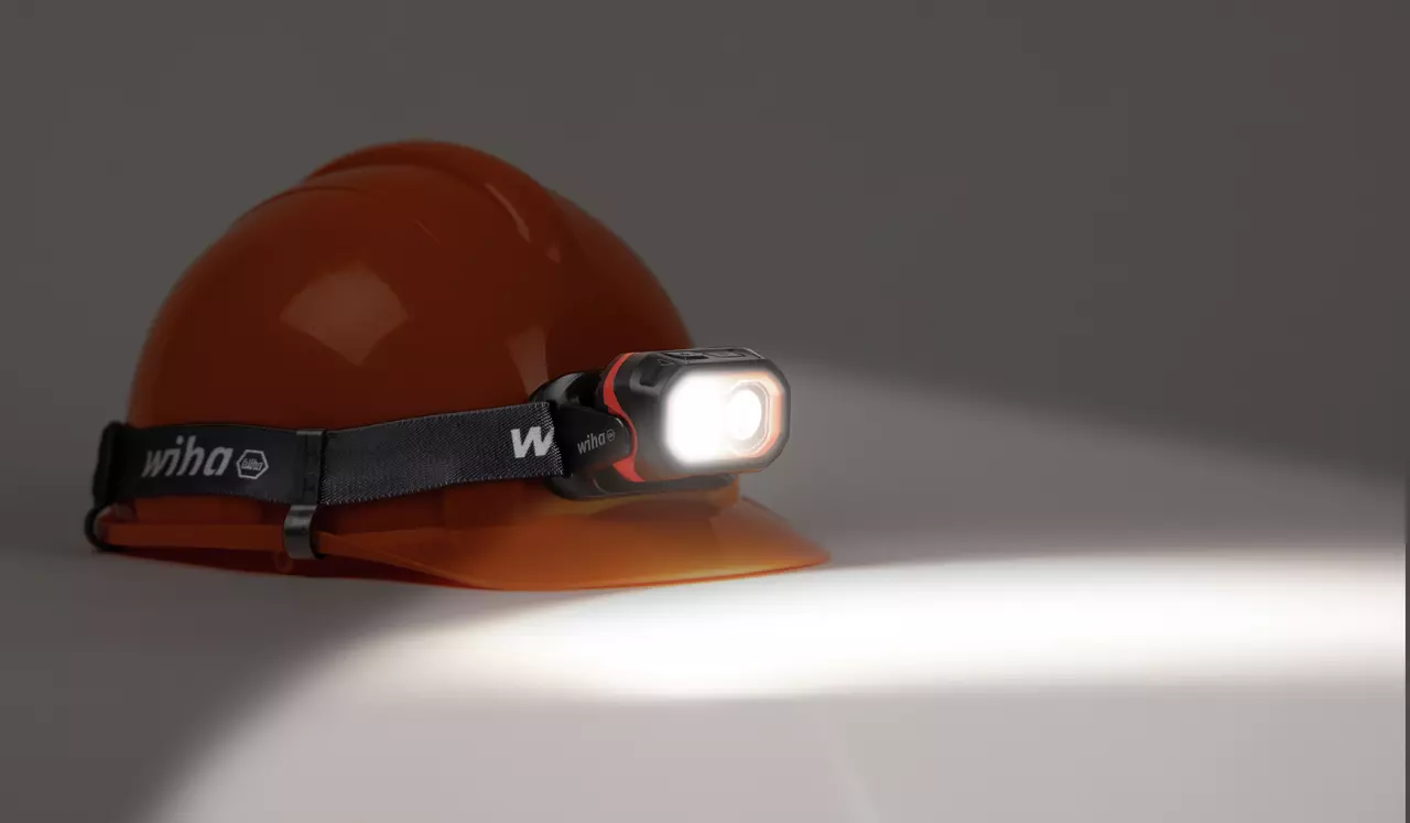 Orange hard hat with a headlamp illuminating to the right.