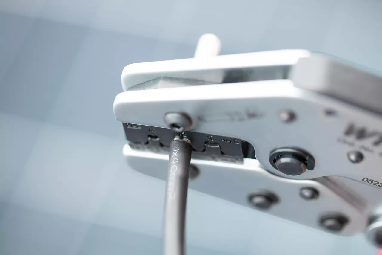 Krympeværktøj med sort kabel, synlige metalbakker.