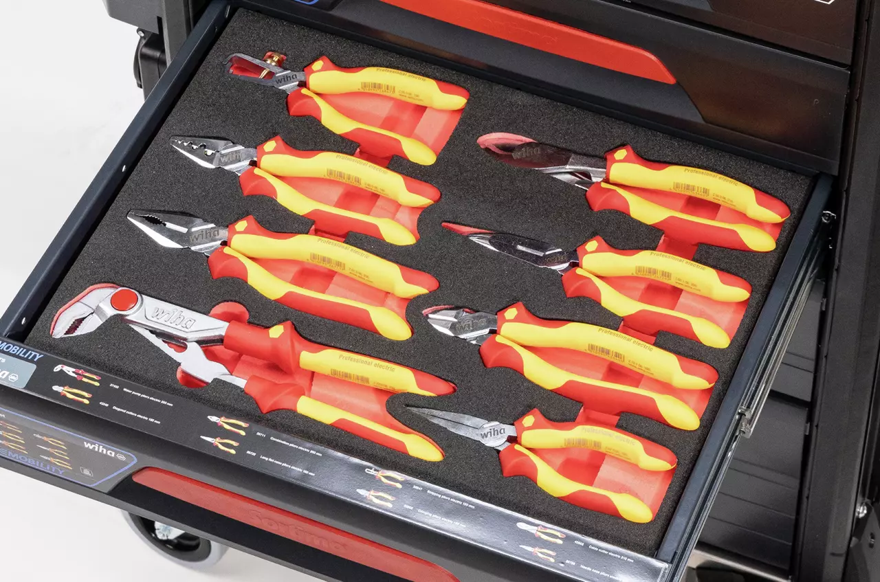Open drawer with organized red and yellow insulated pliers on black foam insert.